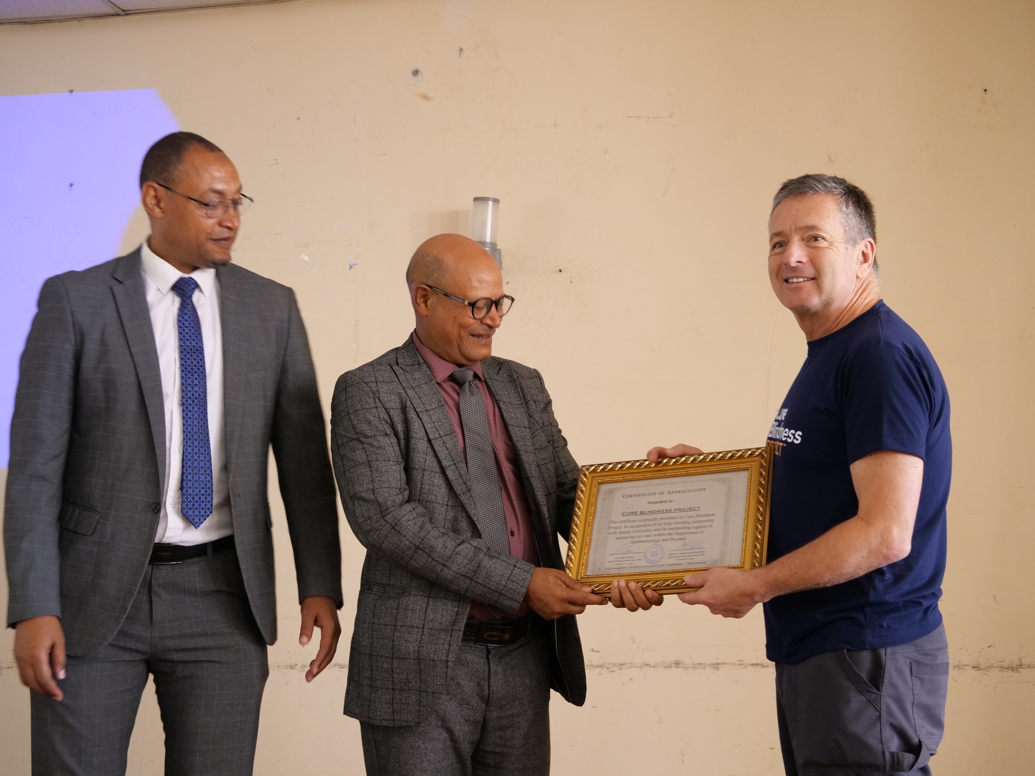 The CEO of Jimma University Medical Center, Prof. Ahmed Zenudin, and Academic Vice President Dr. Tadesse Haptamu present a certificate of appreciation to Dr. Geoff Tabin, Co‑Founder of the Cure Blindness Project.